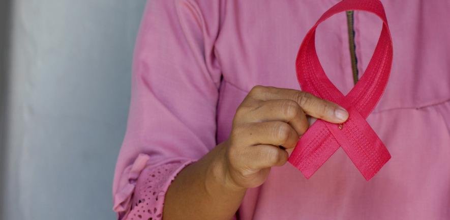 Woman holds pink breast cancer awareness ribbon.
